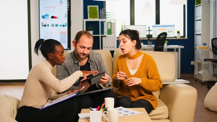 Pearl Lemon sales team collaborating on a digital campaign strategy using a tablet and printed charts.